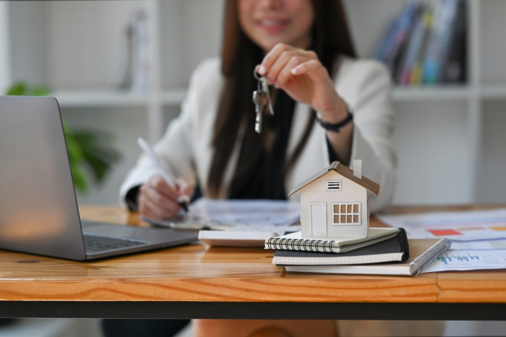 Smiling young woman holding house keys. Mortgage loan and insurance concept.